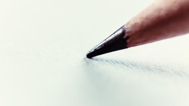 Macro pencil tip resting on blank white paper 
